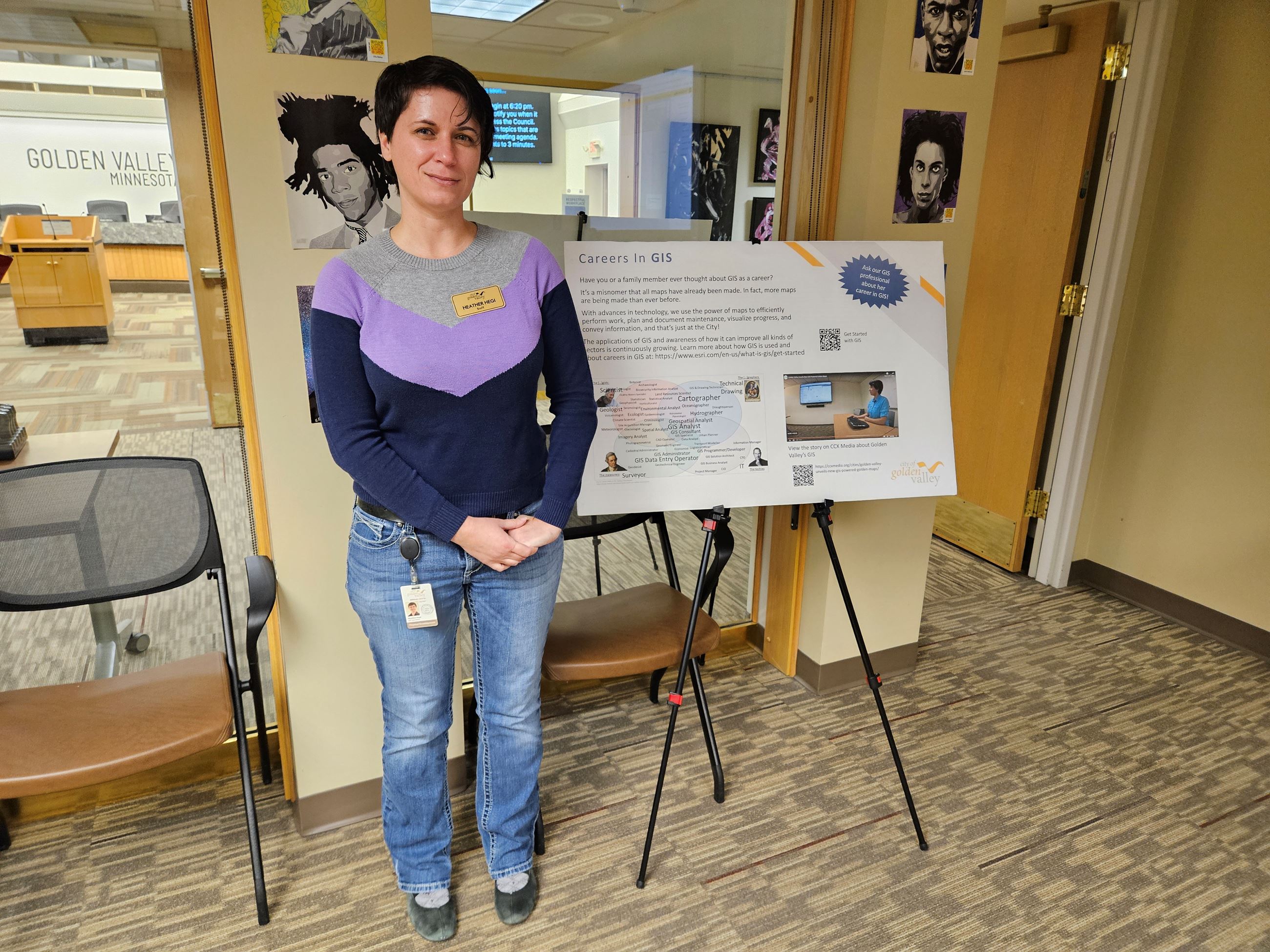GIS Specialist Heather Hegi stands in front of a GIS poster at the GIS Day Open House